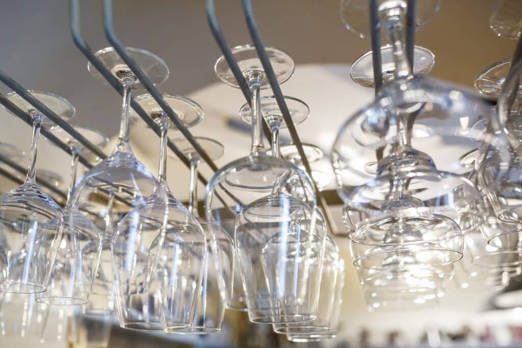 rows of empty glasses hang on reception party table in bar. Close up at row of glasses